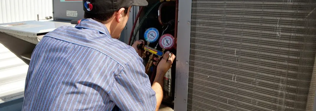 HVAC technician servicing a condenser unit in Camden